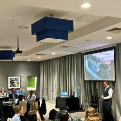 A photo at Gildeas Solicitors first annual conference. The photo shows Director Colin Ferguson addressing the room from behind a podium.