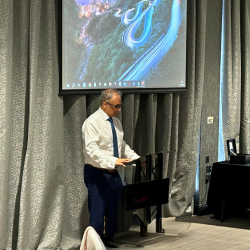 A photo at Gildeas Solicitors first annual conference. The photo shows Director Sanjeev Bali addressing the room from behind a podium.