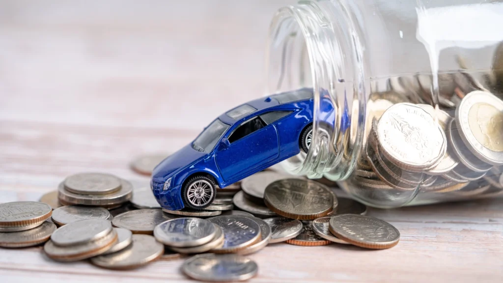 Toy car tipped over beside a glass jar spilling coins, symbolising personal injury compensation, legal fees, and financial claims after a car accident. The image is being used to advertise Gildeas Solicitors, a personal injury firm based in Scotland.