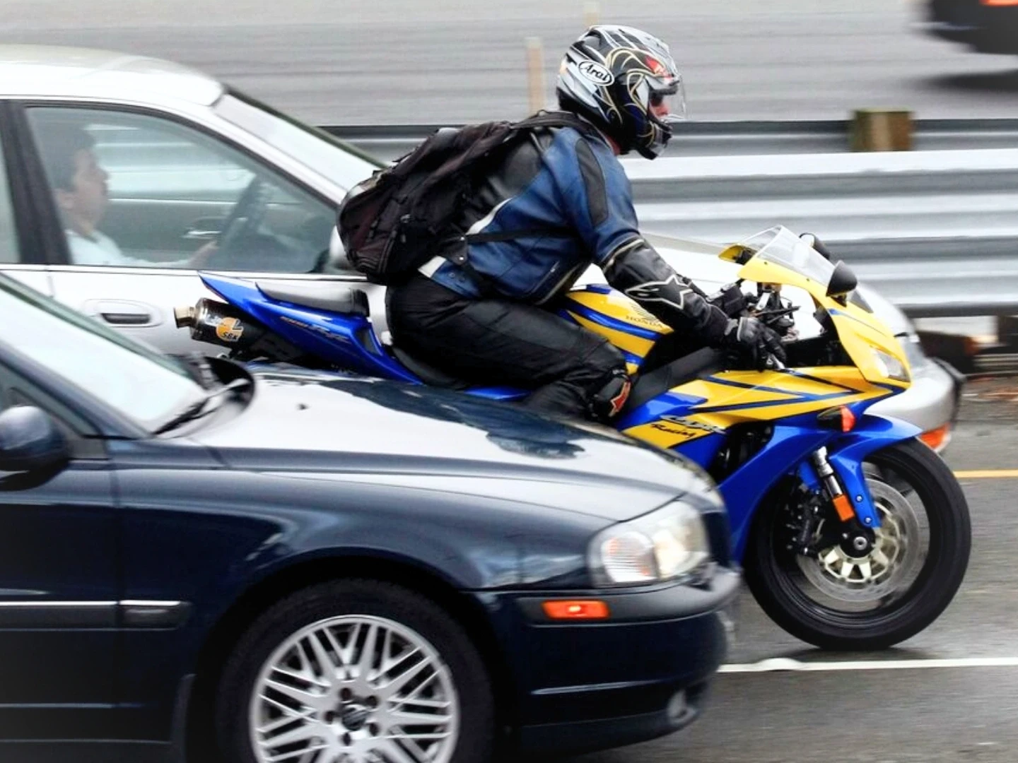A motorcycle speeds between two moving cars, illustrating bike filtering. The image is being used to advertise Gildeas Solicitors, a personal injury firm. They specialise in accident claims in Scotland, including road traffic accidents, motorcycle accidents, cycling accidents, and accidents at work. They are a no win no fee solicitors.
