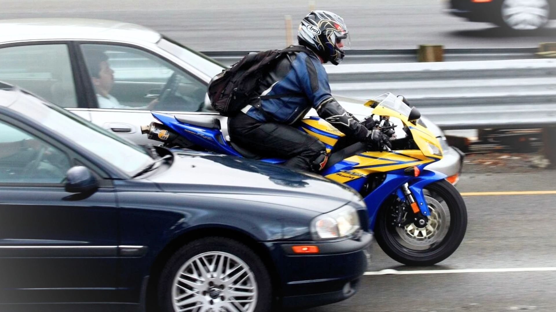 A motorcycle speeds between two moving cars, illustrating bike filtering. The image is being used to advertise Gildeas Solicitors, a personal injury firm. They specialise in accident claims in Scotland, including road traffic accidents, motorcycle accidents, cycling accidents, and accidents at work. They are a no win no fee solicitors.
