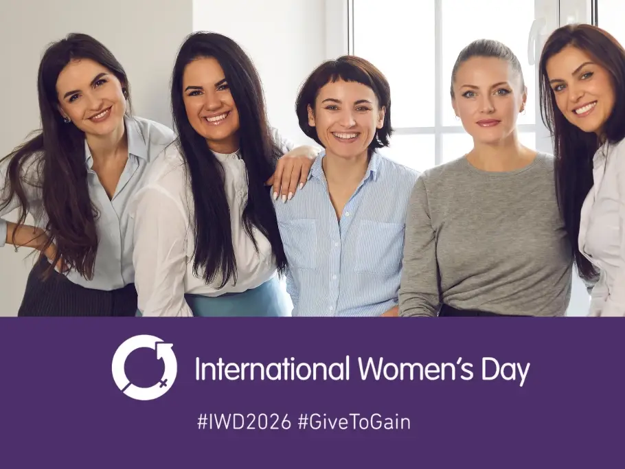 Five professional women standing together and smiling in an office setting, above a purple International Women’s Day banner featuring the IWD symbol and the words International Women’s Day with hashtags IWD2026 and GiveToGain, used by Gildeas Solicitors for International Women’s Day 2026.